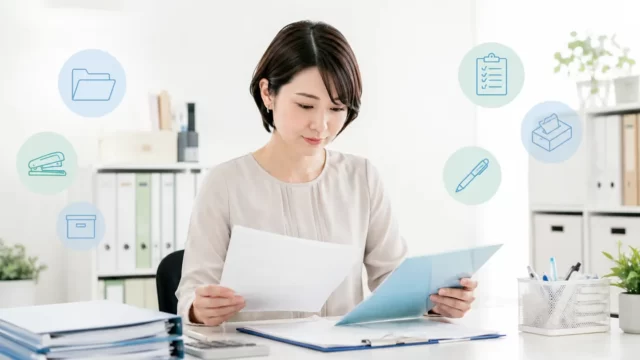 備品台帳と書類を確認する中小企業の総務担当者